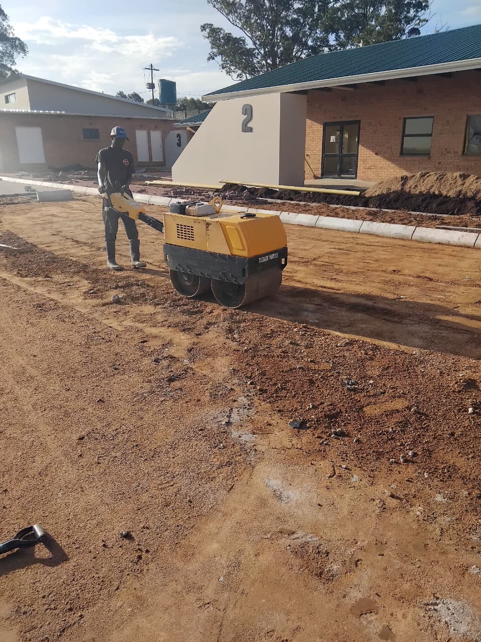 Operator compacting a sub-base with a roller on a construction site